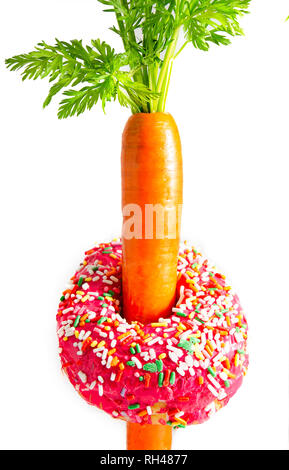 Ein rosa matt Donut umkreist das 'Taille' eines frischen Karotten, 30. März 2016, in Coden, Alabama. Eine mittlere Karotte hat ungefähr 25 Kalorien. Stockfoto