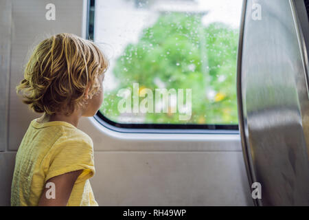Schöne toddler Boy auf der Suche außerhalb der Bahn Fenster, während Sie es bewegen. Gehen auf Ferien und Reisen mit der Bahn im Sommer Stockfoto