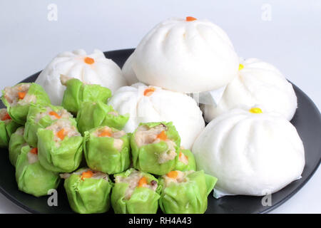 Chinesische beliebte Wüste, Varitirs gedämpft Zeug bun- und grüne Chinesische gedämpft Knödel mit Schweinefleisch in schwarz Platte serviert. Stockfoto