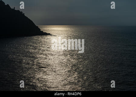 Leuchtturm von San Sebastian bei Sonnenuntergang Hintergrundbeleuchtung und reflektierte Sonnenlicht auf dem Meer Stockfoto