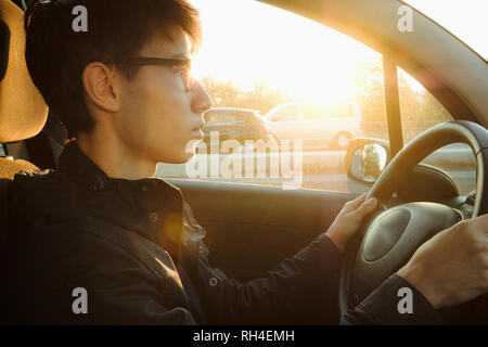 Junger Mann fährt Auto auf Sunny Road Stockfoto