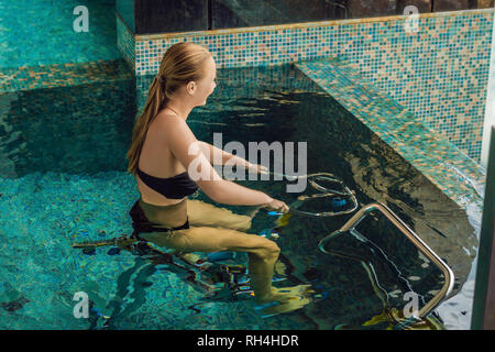 Junge Frau auf dem Fahrrad Simulator unter Wasser im Pool Stockfoto