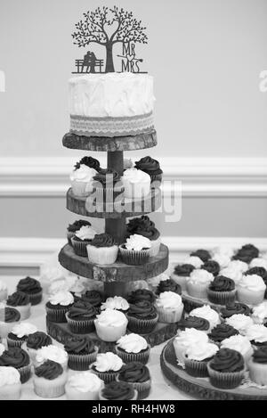 Hochzeitstorte & Cupcakes bei einem rustikalen Themenempfang Schwarz-Weiß-Bild Stockfoto