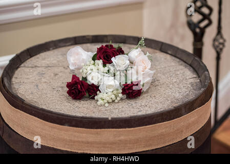 Brautblumenarrangement auf einem rustikalen Holzfass bei einem Hochzeitsempfang in einem Catering-Saal Stockfoto