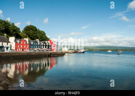 Bunt bemalte Häuser und ihre bunte Reflexionen an Tobermory mit den Kai, der Fährhafen und Hafen an einem sonnigen Sommertag. Stockfoto