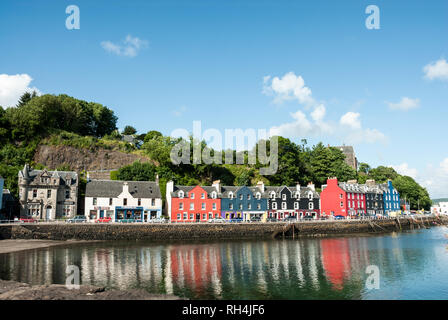 Bunt bemalten Häusern entlang der Hafenfront in Tobermory, Mull, Großbritannien mit ihren hellen Spiegelungen im Wasser. Stockfoto