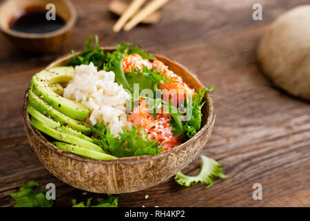 Hawaiian poke Kokosnuss Schale mit gegrillter Lachs Fisch, Reis und Avocado. Gesunde Ernährung Stockfoto