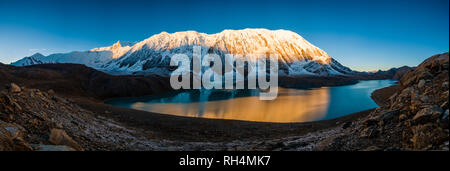 Panoramablick über Tilicho See, die schneebedeckten Gipfel der Kangsar Kang und Tilicho Peak Spiegelung, bei Sonnenaufgang Stockfoto