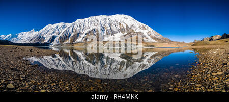 Panoramablick über Tilicho See, die schneebedeckten Gipfel der Kangsar Kang und Tilicho Peak Spiegelung, bei Sonnenaufgang Stockfoto