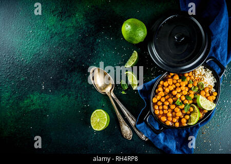 Vegan indisches Essen, süsse Kartoffeln und Kichererbsen in Curry, Chana Masala mit Kalk Schichten und Gewürzen auf dunkelgrünen Tischplatte ciew Platz kopieren Stockfoto