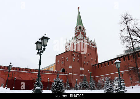 Moskauer Kreml und Schnee Tannen in bewölkten Tag bedeckt, malerischen Blick. Troitskaya Turm mit rotem Stern und Straßenlaternen im Alexandergarten Stockfoto