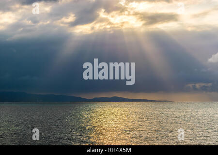 Malerische Landschaft Meer Berg Silhouette der Sonnenstrahlen durch die Wolken. Konzept der Durchbruch, der Hoffnung, Zeichen. Stockfoto