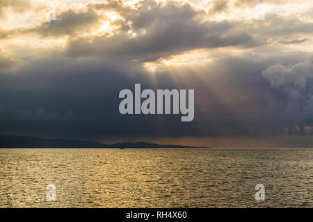 Malerische Landschaft Meer Berg Silhouette der Sonnenstrahlen durch die Wolken. Konzept der Durchbruch, der Hoffnung, Zeichen. Stockfoto