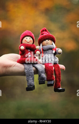 Lustige romantische Paar Puppen aus Holz in knited Verschleiß sitzen auf einem Palm. Stockfoto