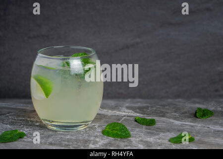 Einen Mojito Cocktail in einem kleinen ovalen Glas garniert mit Minze und Limette auf einem Fels und Stein Stockfoto