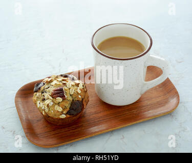 Frischen heißen Kaffee und Pecan oat chocolate Muffin auf kleinen hölzernen Fach gesunden und nahrhaften Snack. Stockfoto