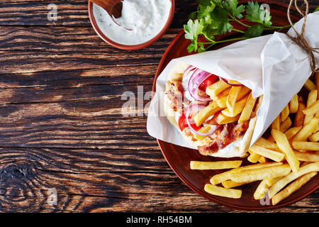 Ansicht von oben der griechischen Souvlaki, Gyros Pita ma mit Hühnerfleisch, Gemüse, Pommes frites auf einen braunen und Tzatziki Sauce in einer Schüssel auf einem urigen ta Stockfoto