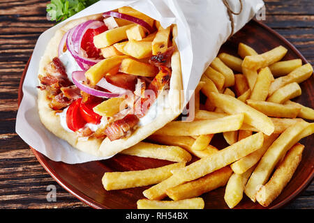 Griechische Souvlaki, Gyros Pita ma mit Hühnerfleisch, Gemüse, Pommes frites auf einem braunen Schild auf einer hölzernen rustikale Tabelle, Ansicht von oben, flatlay, close-up Stockfoto