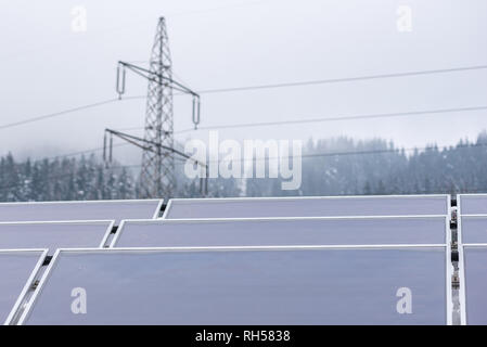 Drei Reihen von Solarzellen auf dem Dach des Hauses platziert. Im Hintergrund sieht man ein Element der Hochspannungsnetzteil-Netzwerk - ein Strommast. Stockfoto