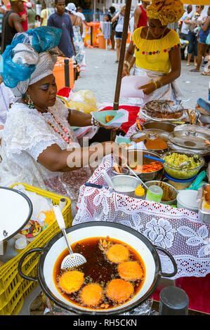 SALVADOR, Brasilien - Februar 2, 2016: Frauen in traditionellen Baiana Kleider fry Brasilianischen acaraje Krapfen in der dicke braune Öl der dende palm Obst Stockfoto