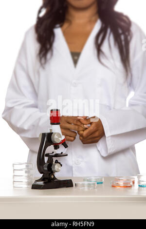 Schwarze weibliche Wissenschaftler tragen Laborkittel mit Mikroskop und Petrischale tun Mikro Biologie Forschung. Sie arbeitet in der Bildung oder medizinische ind Stockfoto
