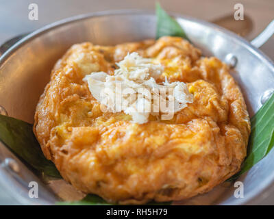 Leckere Thai Stil Omelett mit Krabben Fleisch an der Spitze. Close-up Krabbenfleisch Topping auf omelett Dekoration mit Banana Leaf in Aluminium Pfanne und weißem Porzellan Stockfoto