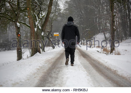 Ein Mann auf der Straße an einem kalten und schneereichen Winter in Franken in Deutschland Stockfoto