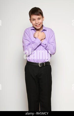 Junge posiert auf weißem Hintergrund, schwarzer Hose und lila Shirt Stockfoto