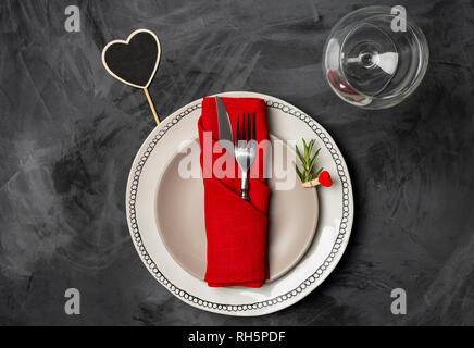 Servierteller für den Valentinstag oder ein romantisches Abendessen mit zwei Teller, Gabel, Messer rot Serviette, Rosmarin und Pin, Glas für Wein und herzförmige Ort Stockfoto