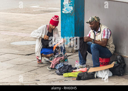 Durban, Südafrika - Januar 6th, 2019: Zwei Männer Handel Kleidung auf der Straße in einer Ecke der City Centre in Durban, Südafrika. Stockfoto