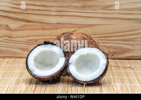 Reif halb Kokosnuss auf einem hölzernen Hintergrund. Coconut Creme und Öl. - Imagem Stockfoto