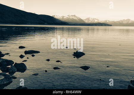Im Alter von Photo Effect Lake Tekapo sunsise über felsige Küste und niedrige Wasserstand des ruhigen friedlichen See in ferne Nähe Alpen. Stockfoto