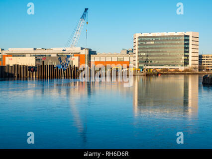 Leith, Edinburgh, Schottland, Großbritannien, 1. Februar 2019. UK Wetter: ungewöhnliches Phänomen eines gefrorenen Wasser in Albert Dock Bassin in Leith Harbour mit Gebäude am Ocean Terminal und der Baustelle mit Kran in der eisigen Oberfläche des Wassers wider Stockfoto