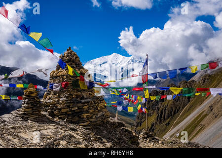 Bunte buddhistische Gebetsfahnen am Thorong Phedi High Camp, die schneebedeckten Gipfel der Annapurna 3 in der Ferne Stockfoto