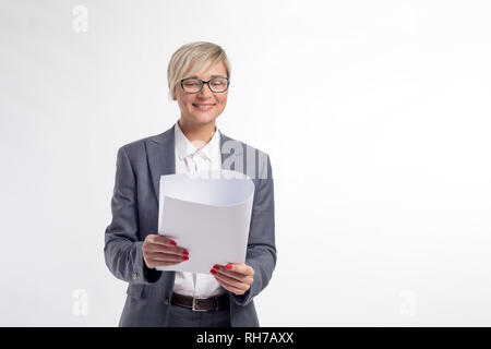 Im mittleren Alter Geschäftsfrau, 40 Jahre alt, in ein weißes Hemd, grauen Anzug und Brille, mit einem roten Maniküre, hält ein weißer Whatman Papier auf einem weißen Ba Stockfoto