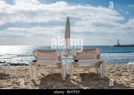Zwei leere Liegestühle am Strand in Costa Teguise. Insel Lanzarote, Spanien. Stockfoto