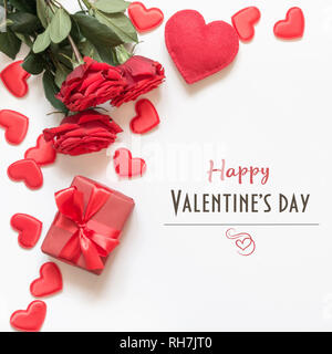 Valentinstag Grusskarten. Zusammensetzung mit Geschenk, Rosen, roten Herzen auf weiße Oberfläche. Ansicht von oben. Stockfoto