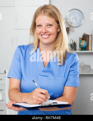 Lächelnd weibliche Krankenschwester in formale Abnutzung Registrierung Informationen in Form Stockfoto