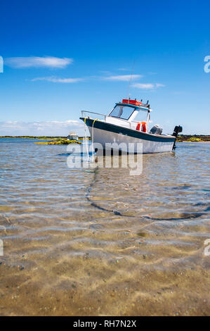 Weiße Boot auf Sand mit Wasser und Felsen im Sommer in Noirmoutier Stockfoto