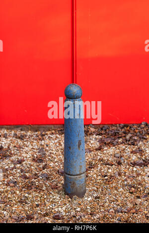 Metall Poller durch Steine vor einem roten Metall umgeben Stockfoto