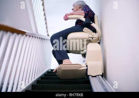 Ältere Frau sitzt auf der Treppenlift zu Hause Mobilität zu unterstützen Stockfoto