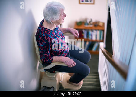 Ältere Frau sitzt auf der Treppenlift zu Hause Mobilität zu unterstützen Stockfoto