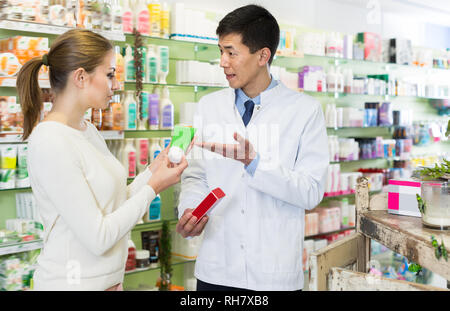 Froh, Frau, Kunde fragt koreanischen Mann Apotheker über die Medikamente in der Apotheke Stockfoto