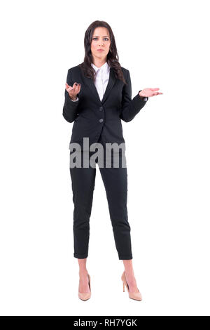 Missverständnis Konzept. Unsicher Business Woman in Black Suit zuckte mit den Schultern. Voller Körper auf weißem Hintergrund. Stockfoto