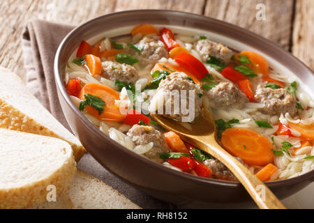 Italienische Suppe mit Pasta orzo, Frikadellen und Gemüse close-up in einem Teller mit frischem Brot serviert. Horizontale Stockfoto