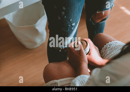 Von oben Ernte Dame in weißem Kleid hält Dose von Getränk und sitzt in der Nähe Frau in Jeans Stockfoto