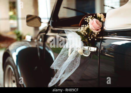 Frische schöne Rose am Griff der Oldtimer Cabrio auf der Straße Stockfoto