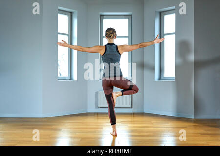 Junge sportliche Frau Üben Yoga, Arbeiten, tragen Sportswear, Hose und Top, Hallenbad in der Nähe, Yoga Studio. Ansicht von hinten Stockfoto