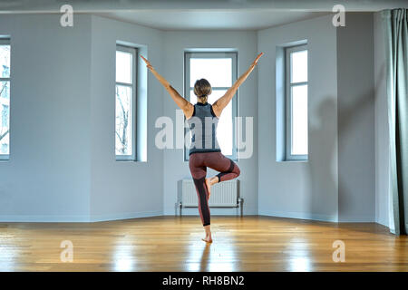 Junge sportliche Frau Üben Yoga, Arbeiten, tragen Sportswear, Hose und Top, Hallenbad in der Nähe, Yoga Studio. Ansicht von hinten Stockfoto