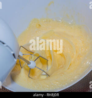 Elektrische Mixer schlagen einige Eier in eine Schüssel für einen Kuchen Stockfoto